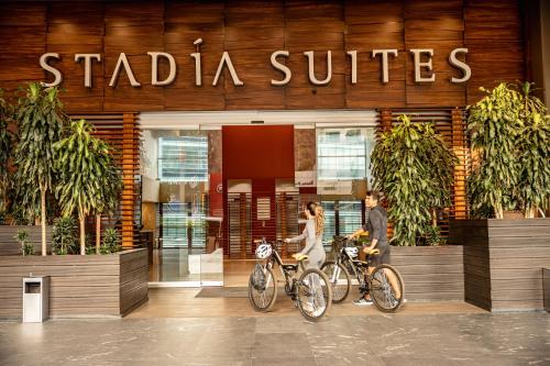 two people walking their bikes in front of a building at Stadia Suites Mexico City Santa Fe in Mexico City