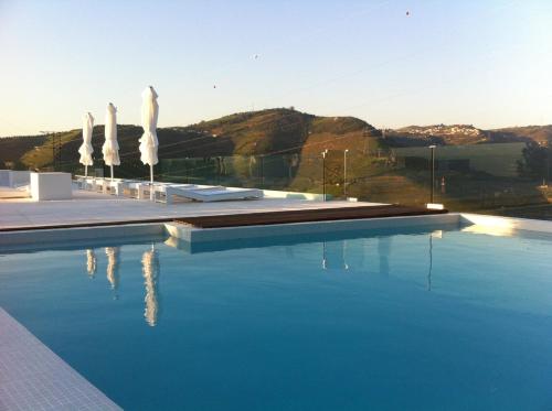 a swimming pool with umbrellas on a building at Quinta De Casaldronho Wine Hotel in Lamego