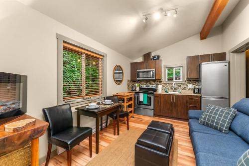 a living room with a blue couch and a kitchen at JDF Waystation Cabin - Garden View - Pet Friendly in Port Renfrew