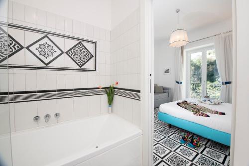a bathroom with a tub and a bed and a window at Villa Guarracino Amalfi in Amalfi