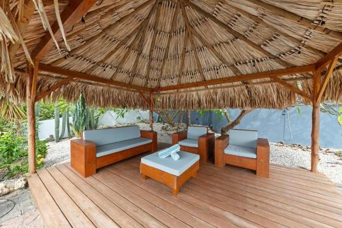 a wooden deck with chairs and a thatched roof at Villa Strelitzia in Dorp Soto