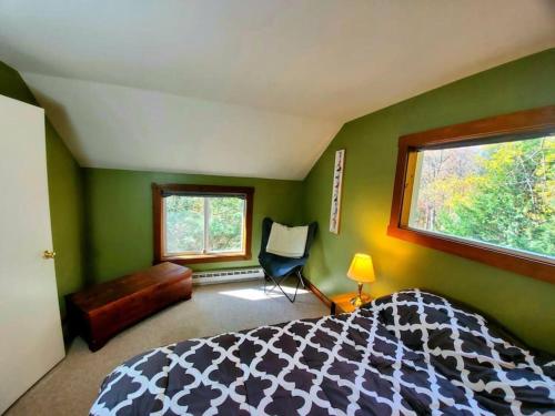 a bedroom with green walls and a bed and a window at Fiddlehead Greens in Warren