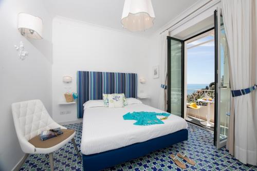 a bedroom with a bed and a chair and a window at Villa Guarracino Amalfi in Amalfi