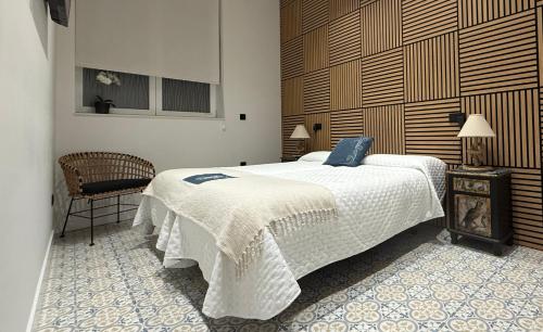 a bedroom with a large white bed and a chair at Alojamiento EL ESPOLON in Alba de Tormes