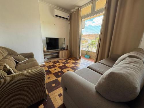 a living room with two couches and a flat screen tv at Apto Pet Friendly com Ar condicionado no Centro in Bagé