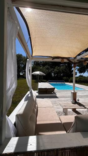 a covered patio with a couch and a swimming pool at Les Granges in Vigoulant