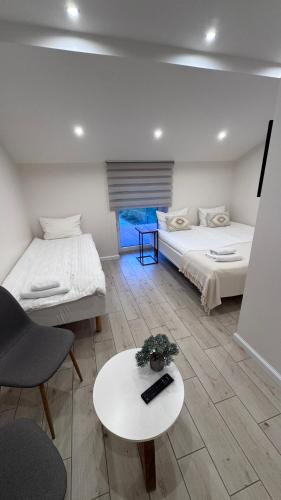 a room with two beds and a table and a couch at Ventė Stay apartment in Ventė