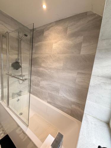 a bathroom with a shower and a tub with a glass door at Precious House 4 in Leicester