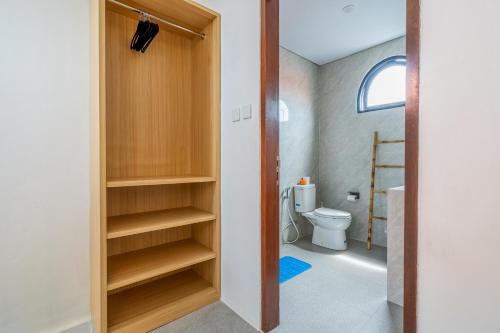 a bathroom with wooden shelves and a toilet at Manik Tropicana Loft in Canggu