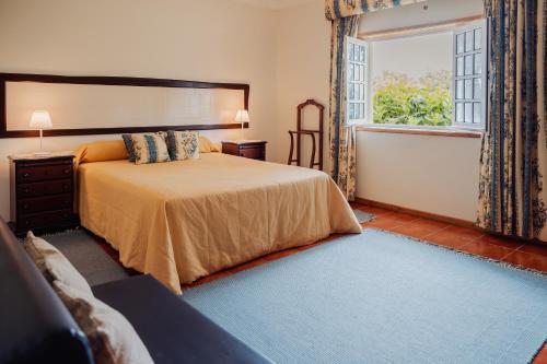 a bedroom with a large bed and a window at Quinta do Pinheiral in Favões