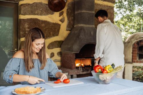 a woman cutting tomatoes on a table in front of a stone oven at Quinta do Pinheiral in Favões