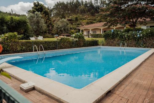 a swimming pool with blue water in a yard at Quinta do Pinheiral in Favões