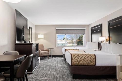 a hotel room with two beds and a desk and a television at Kelly Inn Billings in Billings