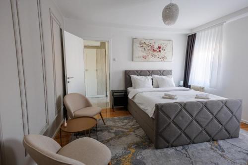 a bedroom with a large bed and two chairs at Apartman Helena - Self check in in Osijek