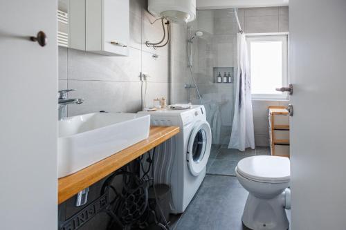 a bathroom with a sink and a washing machine at Apartman Helena - Self check in in Osijek