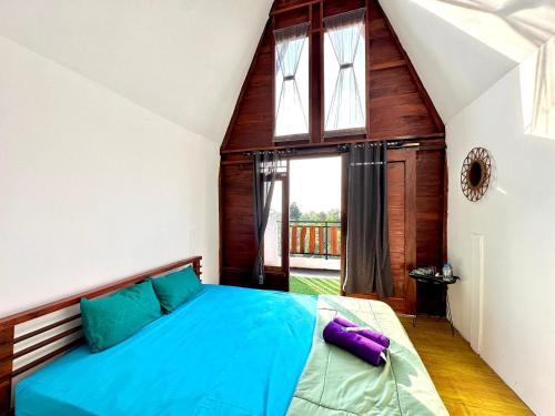 a bedroom with a blue bed in a room with a window at KeJogja Homestay in Grigak
