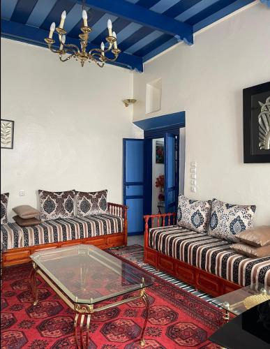 a living room with two couches and a glass table at Meryem Appartement in Essaouira