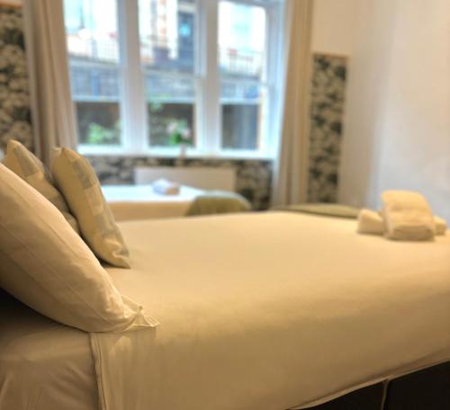 a bed with white sheets and pillows next to a window at Piccolo in Glasgow
