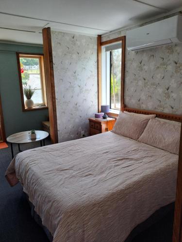 a bedroom with a large bed and two windows at Fieldview Arapuni B&B in Putaruru