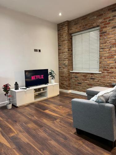 a living room with a television and a brick wall at New & Modern 2-Bed Flat in City Centre in Nottingham