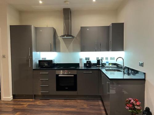 a kitchen with stainless steel appliances and black counter tops at New & Modern 2-Bed Flat in City Centre in Nottingham
