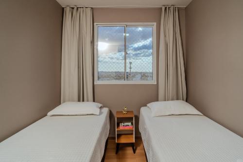 two beds in a small room with a window at Apto Completo BH ARENA MRV - Ar Condicionado e Estacionamento in Belo Horizonte