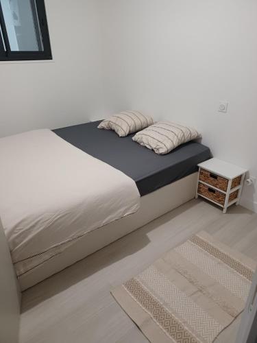 a bed with white sheets and pillows and a table at Le Doudou, Charmant T2 avec Terrasse et Climatisation in Marmande