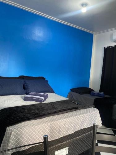 a bedroom with a blue wall and two beds at Residencial Monteiro Luna in Benevides