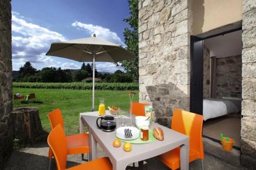 a white table with orange chairs and an umbrella at ZEcamping 3 étoiles animaux acceptés piscine et Canoë Kayak in Chambonas
