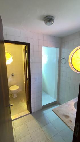 a bathroom with a toilet and a glass door at Pousada Por do Sol in Teresópolis