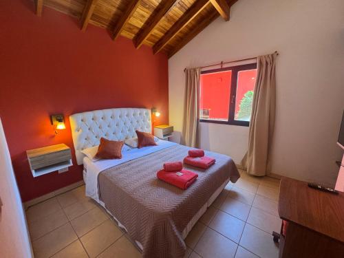 a bedroom with a bed with two red towels on it at Cabaña La Pinta in Santa Teresita