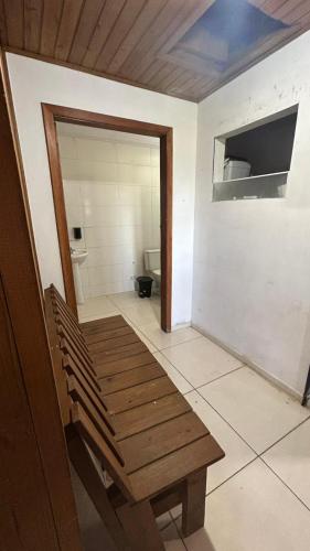 a wooden bench in a room with a bathroom at canto da lagoa in Garopaba