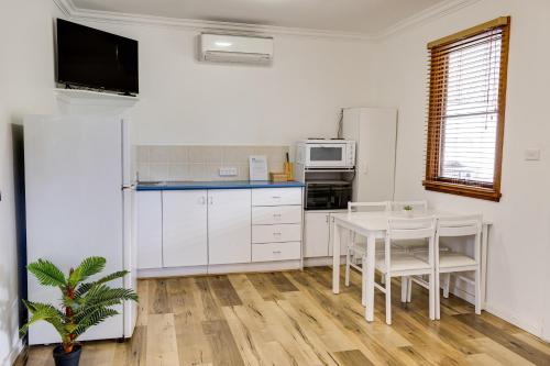 a kitchen with white appliances and a table and chairs at Seachange Parks Lake Conjola in Green Island