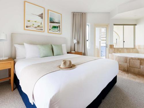 a bedroom with a large white bed with a hat on it at Mantra Zanzibar in Mooloolaba