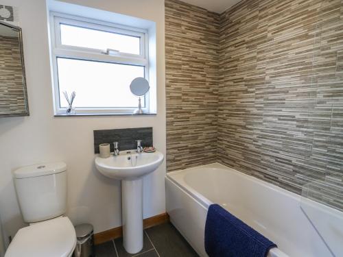 a bathroom with a sink and a toilet and a bath tub at Yr Orsedd in Holyhead