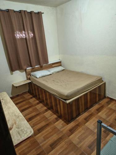 a bedroom with a bed with a window and a wooden floor at Pousada Rancho in Angra dos Reis