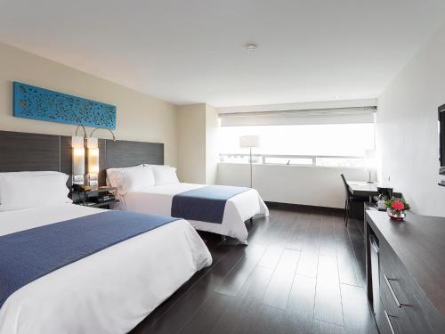 a hotel room with two beds and a window at Hotel bh El Poblado in Medellín