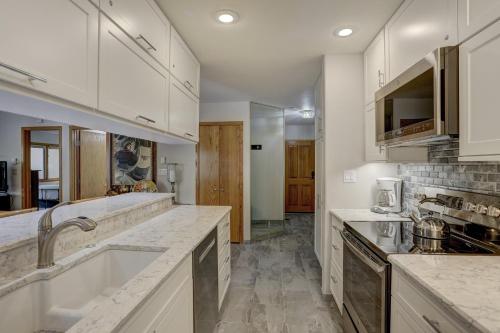 a kitchen with white cabinets and marble counter tops at Townsend Place, A Vail Resorts Property in Beaver Creek