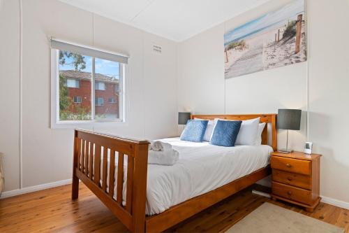 a bedroom with a wooden bed and a window at Sunbeam Cottage on the Lake in Toukley