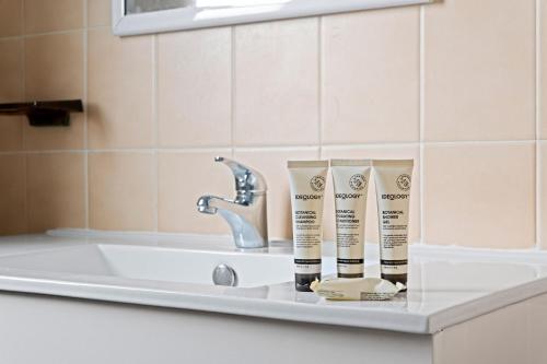 a bathroom counter with two bottles ofodorizers and a sink at Sunbeam Cottage on the Lake in Toukley