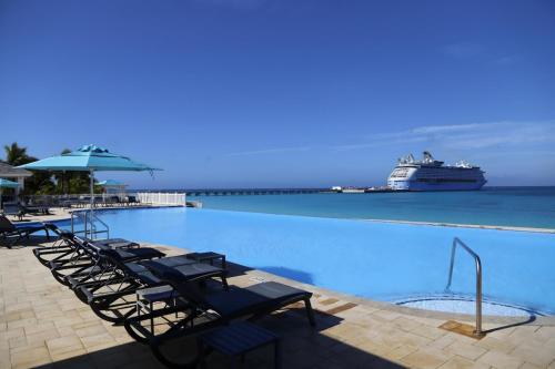 a large swimming pool with a cruise ship in the ocean at Amamare Waterfront Villa | Pool + Private Dock in Bailey Town