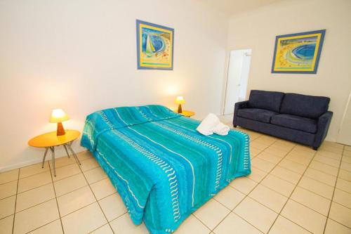 a bedroom with a blue bed and a couch at Breakaway • Central Studio for 4 • Beach • Pool in Agnes Water