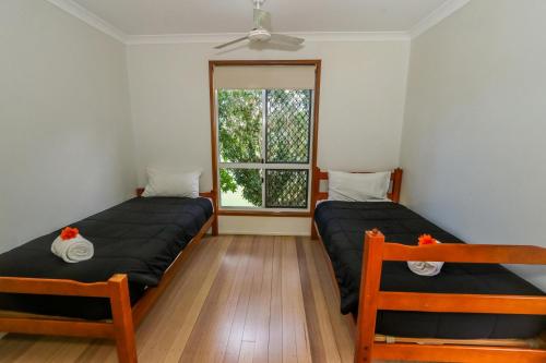 two beds in a room with a window at McLeods • Pet-Friendly Central Beach House for 6 in Agnes Water