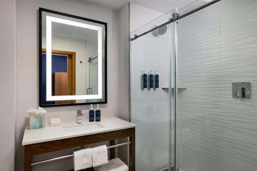 a bathroom with a sink and a shower with a mirror at Four Points by Sheraton Austin Airport in Austin
