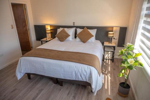 a bedroom with a large white bed with pillows at Hotel Auramia in Punta Arenas