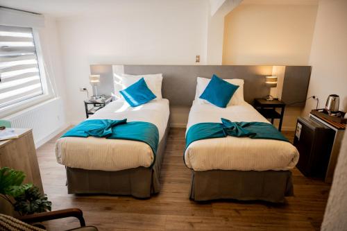 two beds in a room with blue pillows on them at Hotel Auramia in Punta Arenas