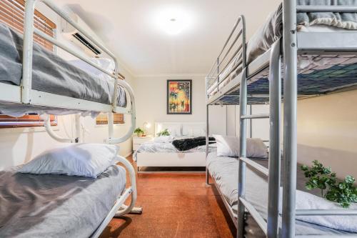 a room with three bunk beds and a bedroom at On Agnes Time • Beach House for 10 • BBQ Deck • Walk to Beach in Agnes Water