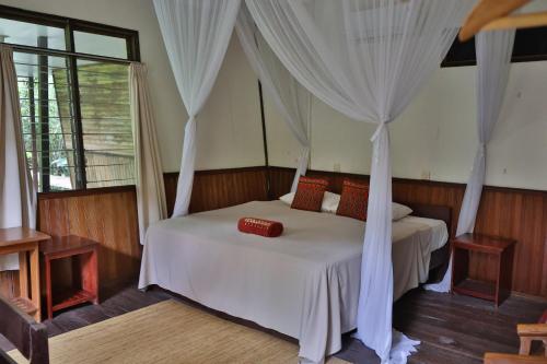 a bedroom with a white bed with a canopy at Rimba Orangutan Ecolodge in Kampungcina