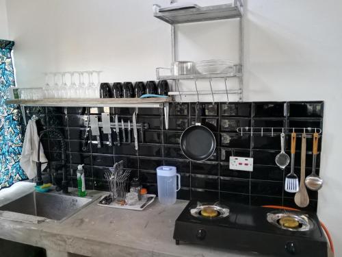 a kitchen with a sink and a black tiled wall at Longonot Cabin in Longonot