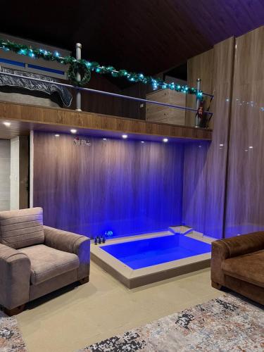 ein Wohnzimmer mit einem großen blauen Pool in der Mitte des Raumes in der Unterkunft Aroma Chalet in Ḩūmīn al Fawqā